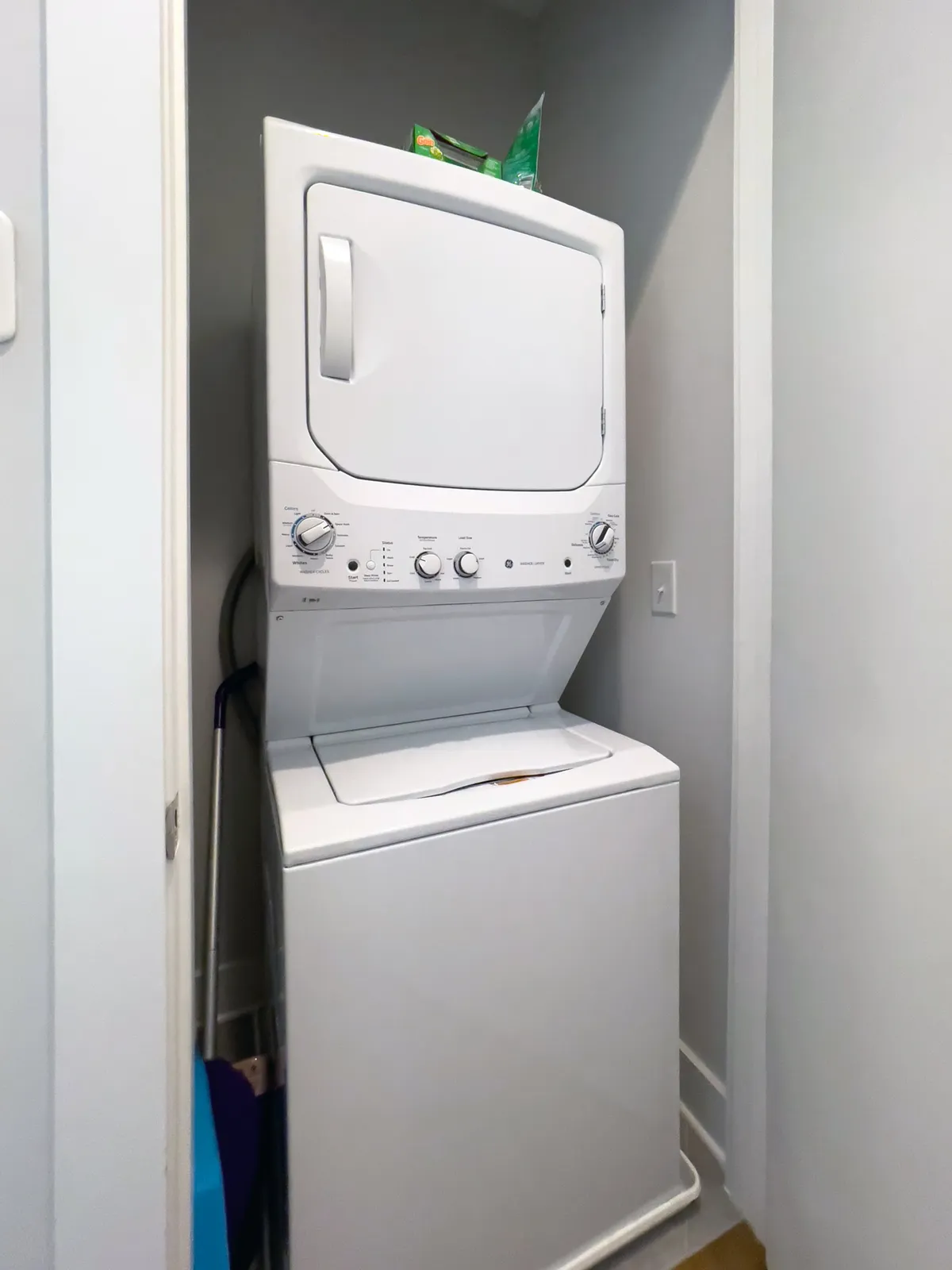 This image features a stacked washer and dryer in a dedicated laundry space, accompanied by laundry detergent and cleaning supplies neatly organized on nearby shelves. The area is clean, efficient, and immediately conveys a sense of convenience and readiness for guests.