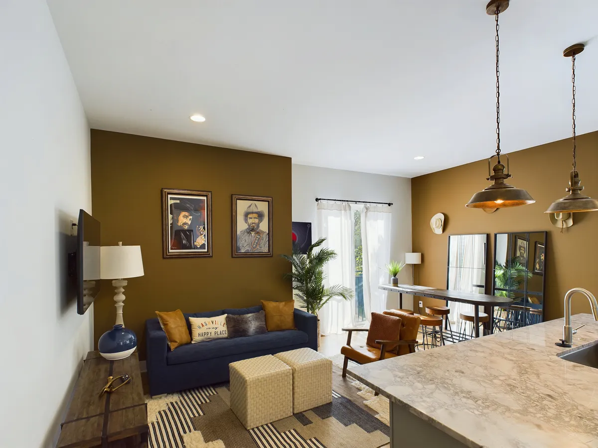 A cozy living and dining area adorned with wall art, a comfortable sofa, and a stylish dining table. The room exudes warmth and invites relaxation or social conversation, with artwork adding a touch of local flavor.