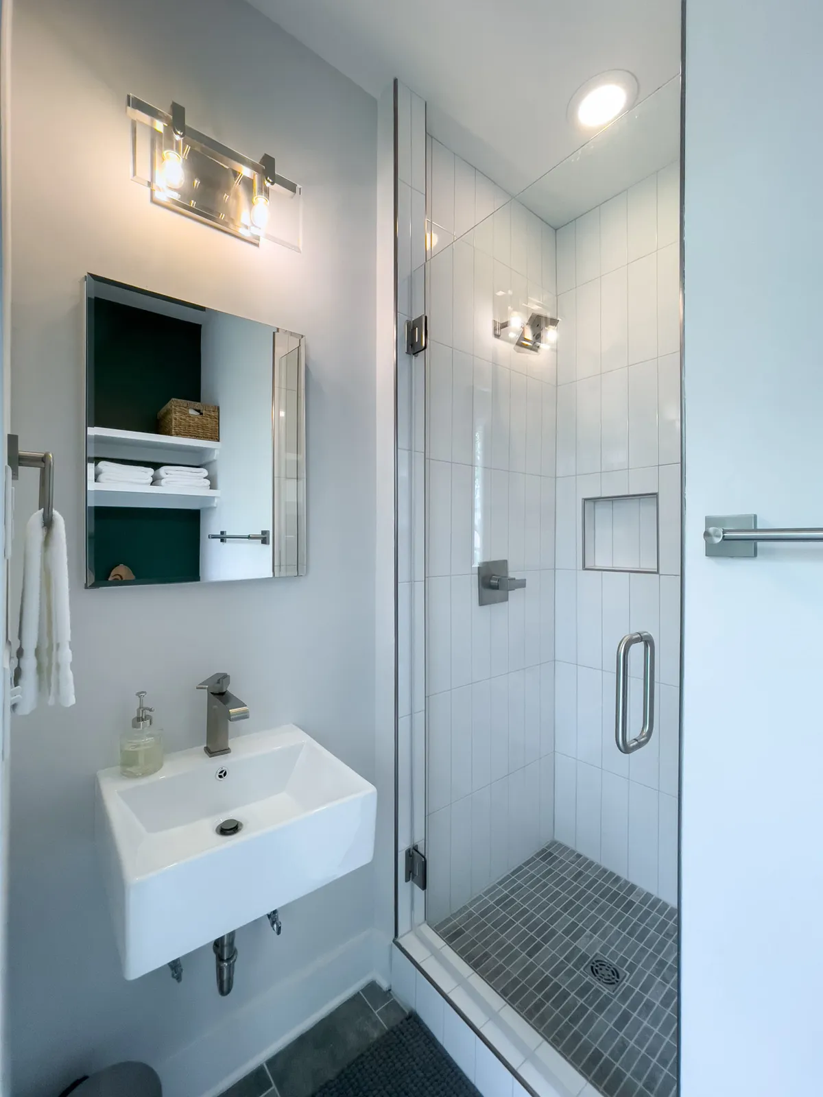 A modern, refreshingly bright bathroom with a glass shower enclosure, sleek sink, and a large mirror. The space is clean and serene, inviting guests to unwind and recharge.