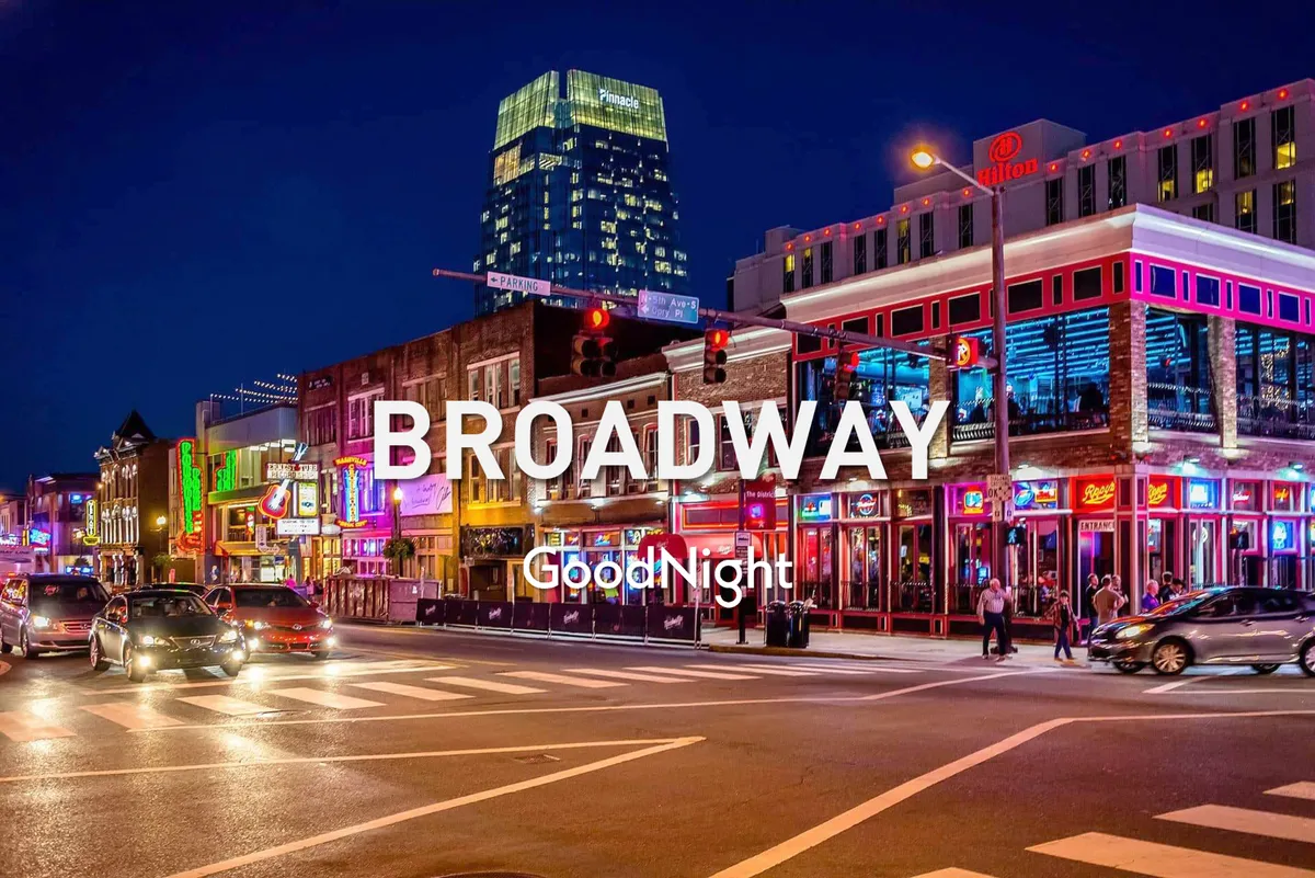 A bustling city street illuminated by bright neon signs, with people exploring the area and a high-rise building in the background. The atmosphere is lively, suggesting an area rich with nightlife, music, and cultural experiences.